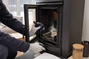 Technicien contrôlant l’intérieur d’un poêle à granulés avant un devis de dépannage