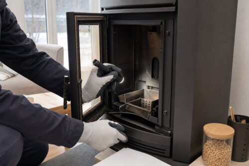 Technicien contrôlant l’intérieur d’un poêle à granulés avant un devis de dépannage