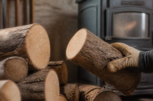 Bûches de chauffage inspectées à côté d’un poêle à bois éteint