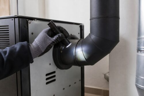 Technicien contrôlant le raccord de fumées d’un poêle à granulés
